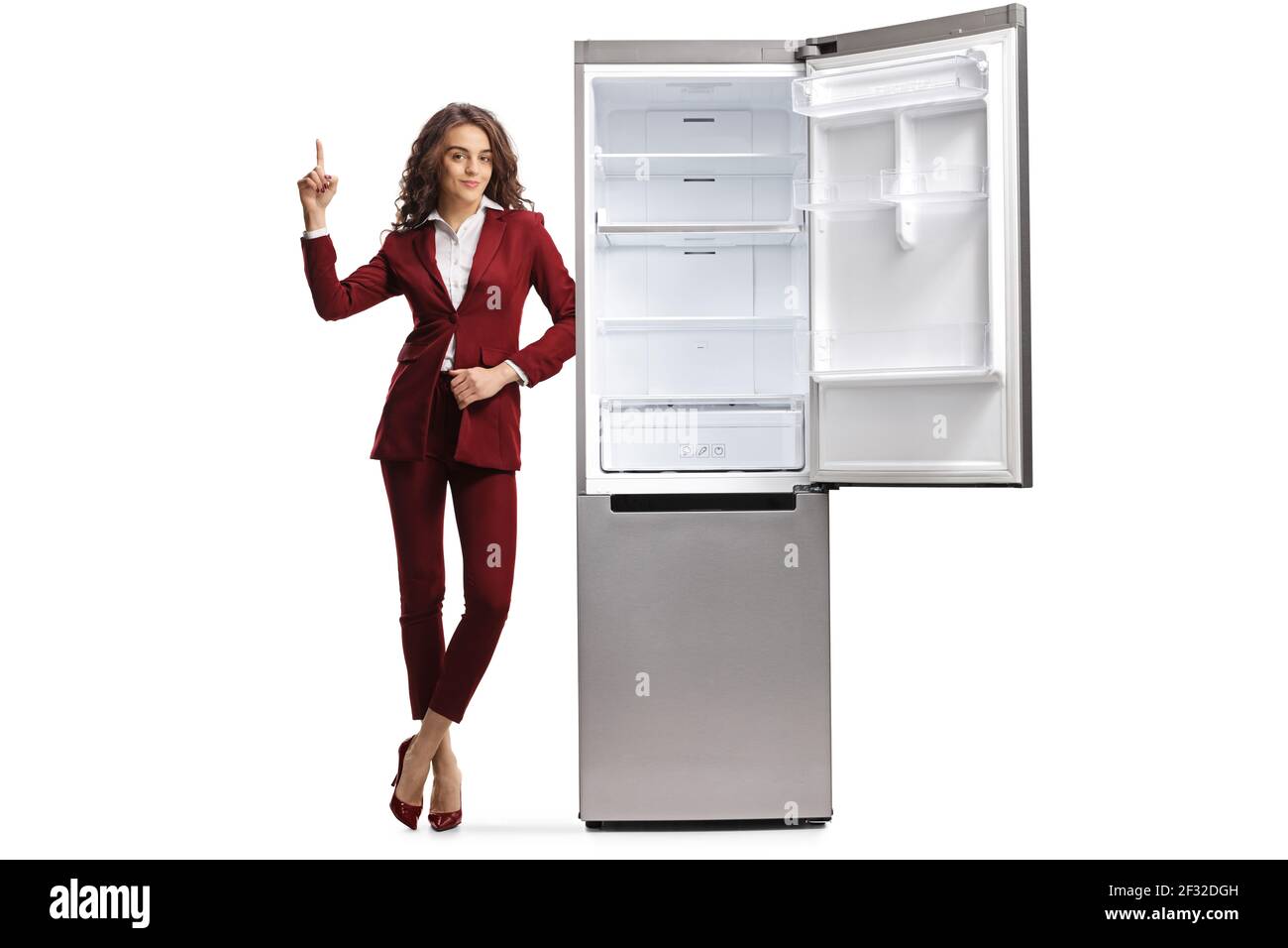 Ritratto a lunghezza intera di una giovane donna professionista che punta in su e appoggiandosi su un frigorifero isolato su sfondo bianco Foto Stock