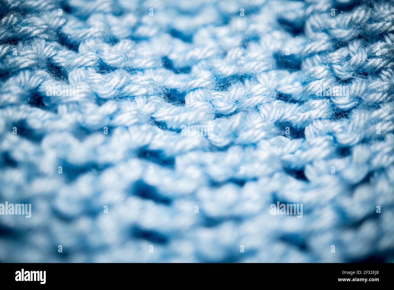 Un'estrema ripresa ravvicinata con messa a fuoco selettiva di un pezzo di tessuto lavorato a maglia blu profondo. Foto Stock