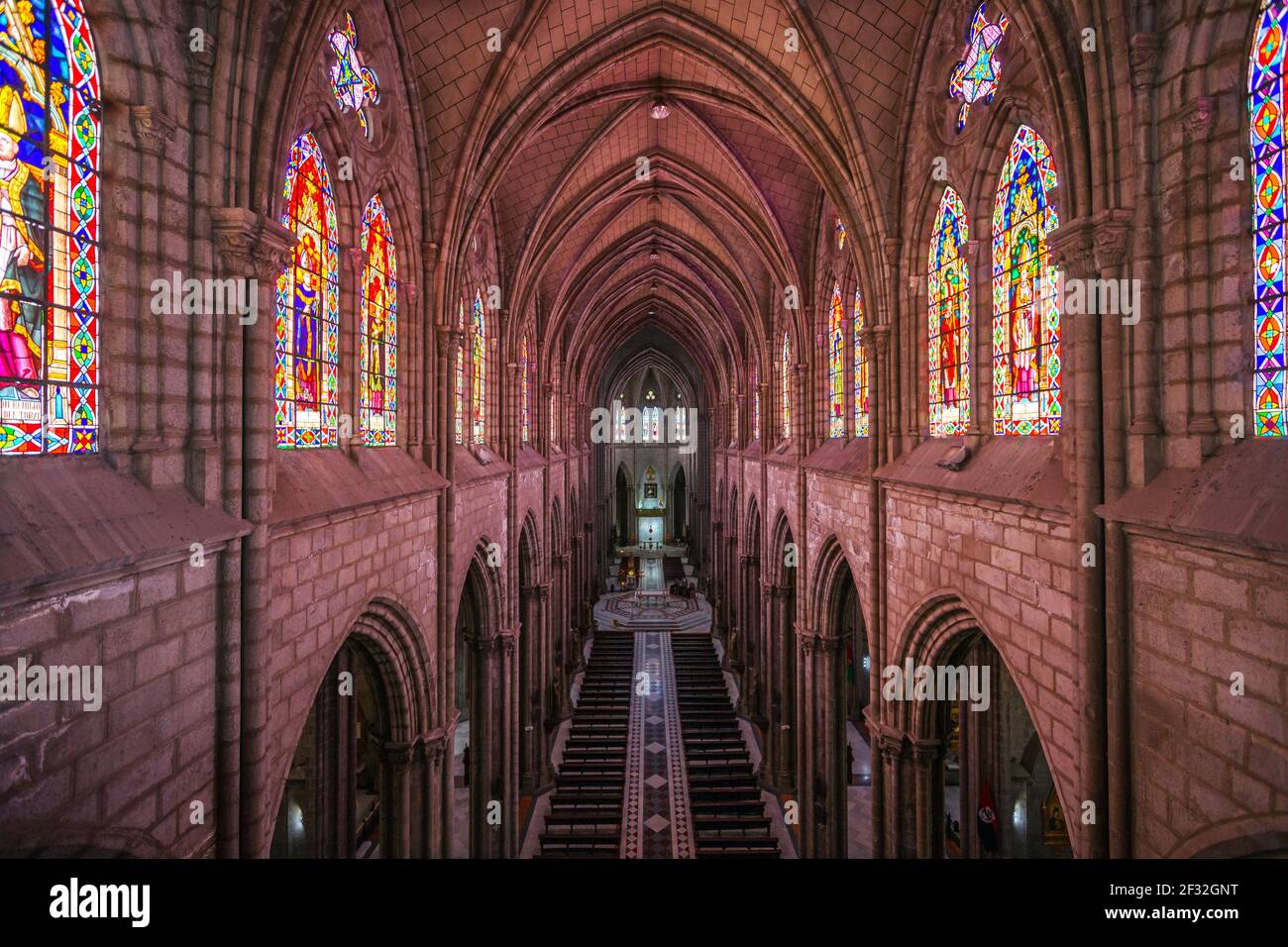 Vista lungo l'unica lunga navata centrale di Basílica del Vota Nacional a Quito, Ecuador, con una cupola e vetrate al santuario Foto Stock