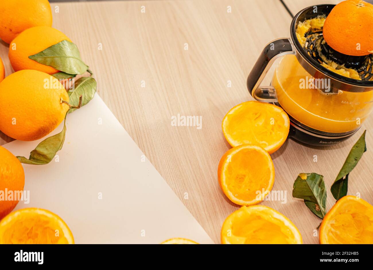 Versare il succo d'arancia fresco. Parti arancioni schiacciate su tavola di legno. Primo piano bicchiere di succo d'arancia fresco. Dieta sana e vegetariana, bevanda alla frutta o Foto Stock