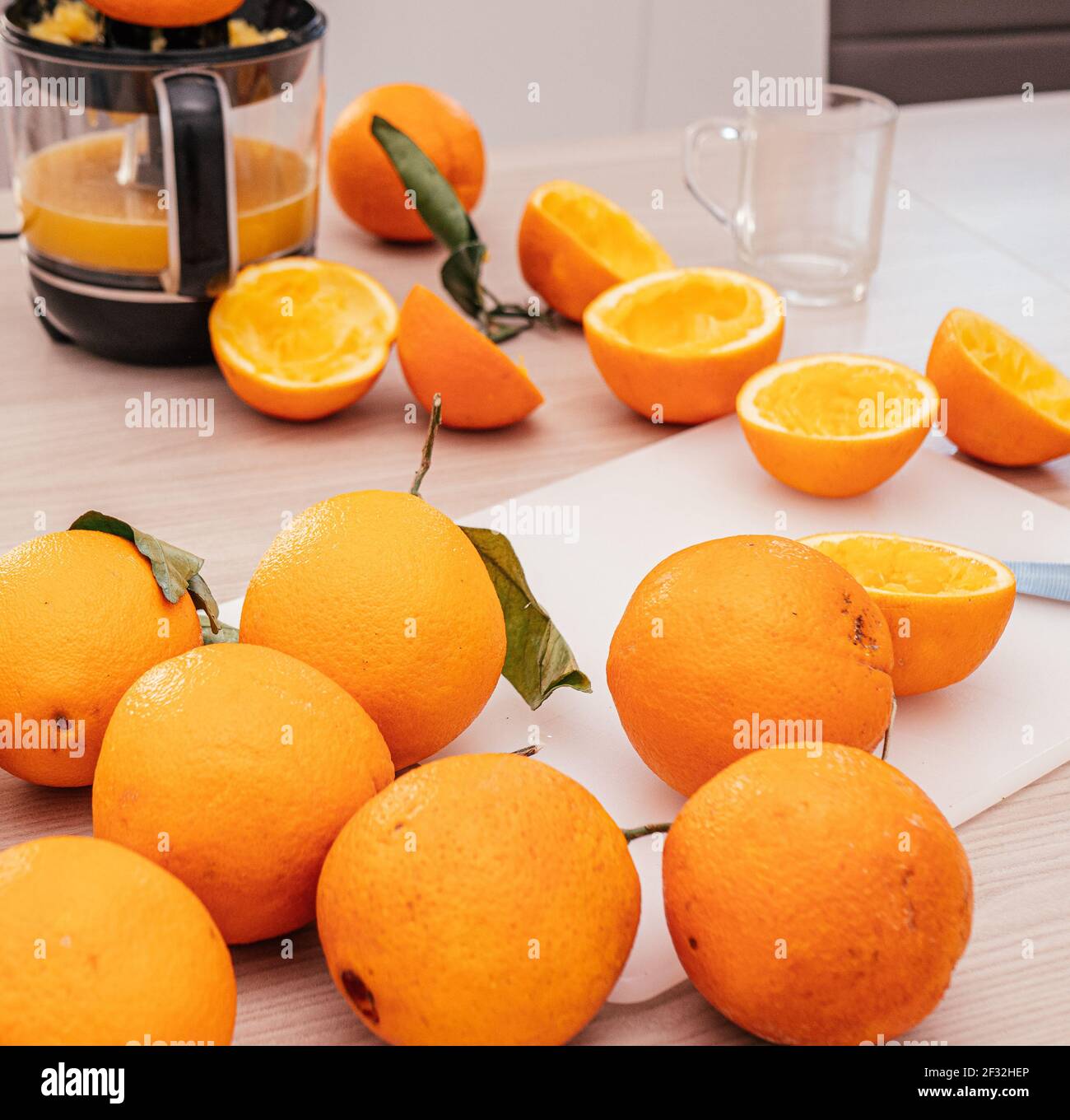 Versare il succo d'arancia fresco. Parti arancioni schiacciate su tavola di legno. Primo piano bicchiere di succo d'arancia fresco. Dieta sana e vegetariana, bevanda alla frutta o Foto Stock