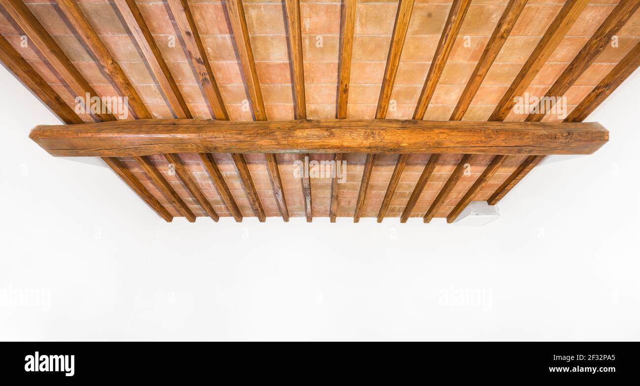 Soffitto tradizionale in legno di quercia toscano, motivi in mattoni rossi e pareti bianche come copyspace. Interni rurali italiani classici. Foto Stock
