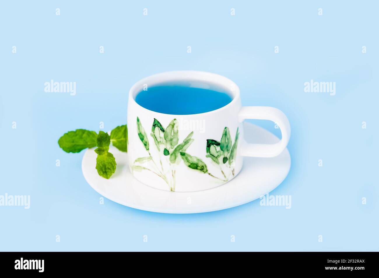 Tazza di porcellana di tè biologico con fiore di pisello blu con farfalla foglia di menta Foto Stock
