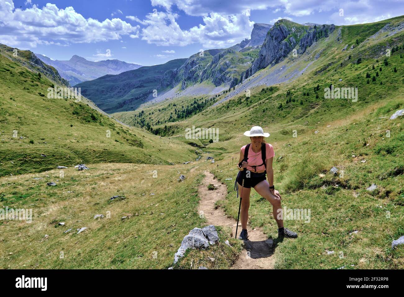 Donna escursionista in un paesaggio di montagne e praterie. Parco Naturale Valles Occidentales. Valle di Hecho. Catena montuosa dei Pirenei, Huesca, Aragona, Spagna, E. Foto Stock