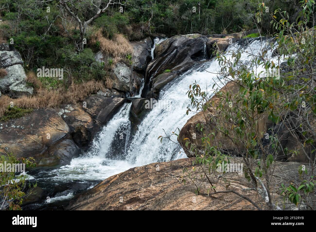 Il flusso d'acqua della cascata di Pimenta che scende sopra le principali formazioni rocciose a goccia nella foresta di Serra do Mar, nella campagna di Cunha Foto Stock