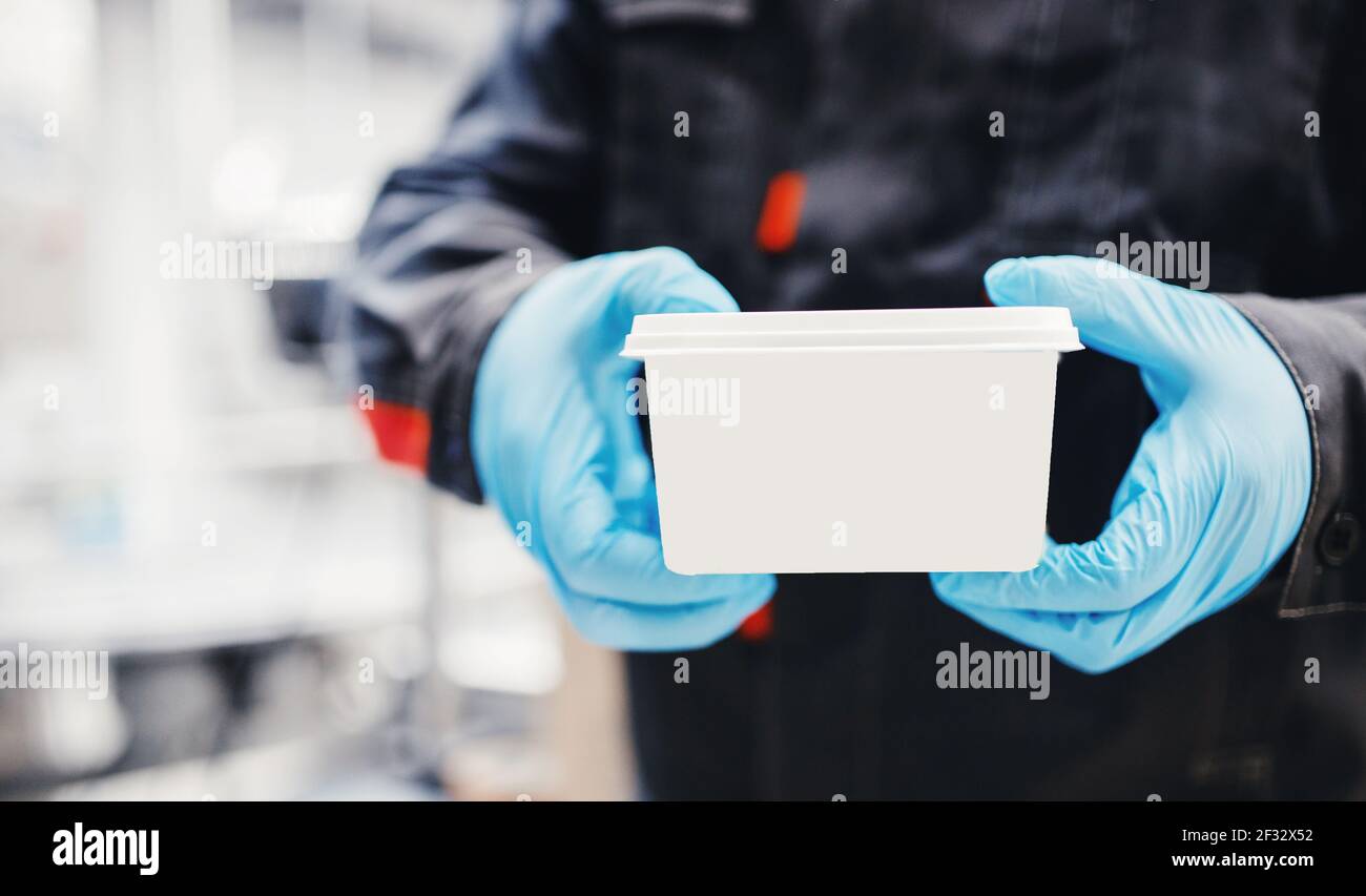 Il tecnico di fabbrica tiene il prodotto finito in una scatola bianca con il logo e lo spazio per la copia. Foto Stock