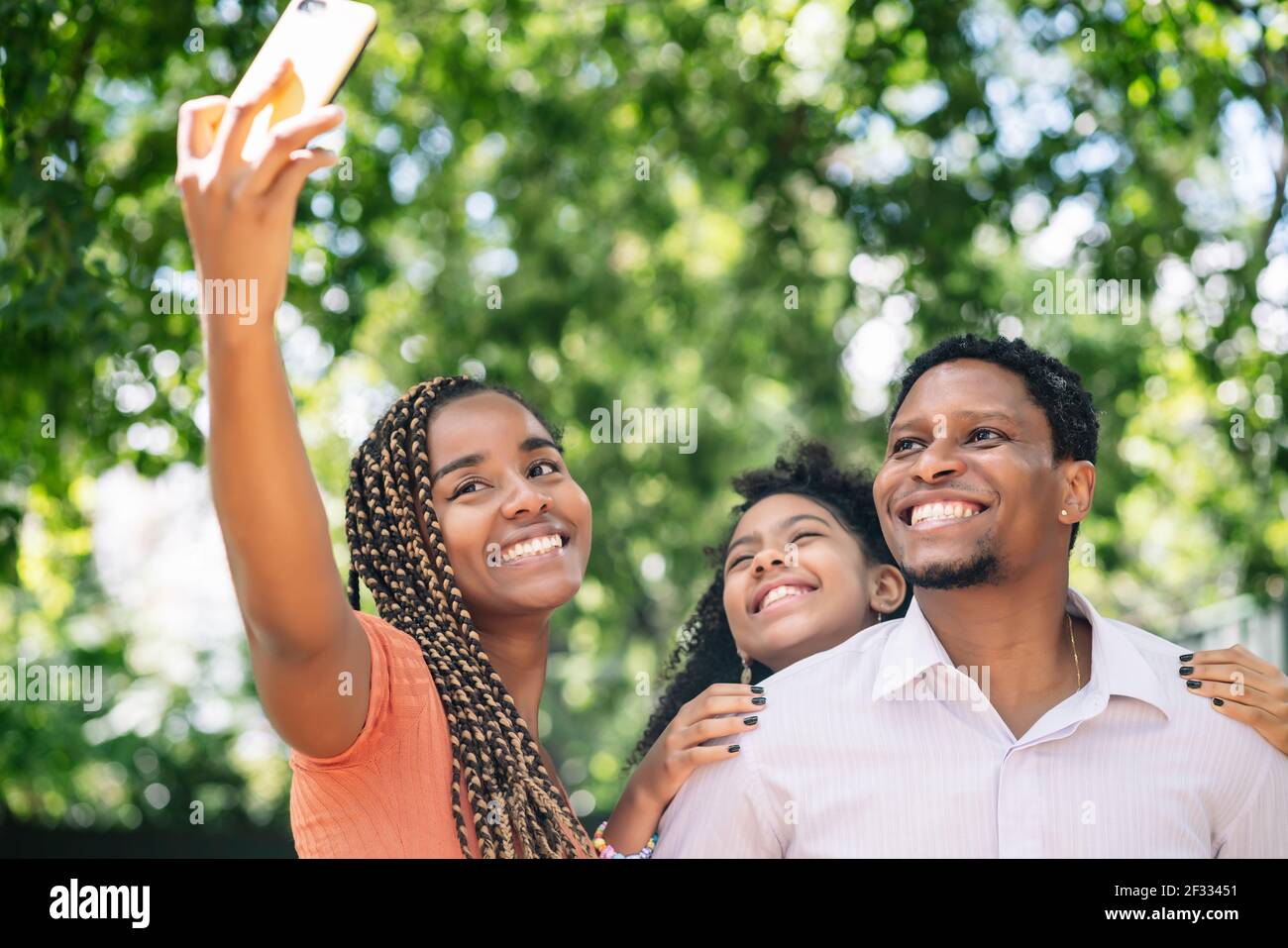 Famiglia che prende un selfie con un telefono cellulare al parco. Foto Stock