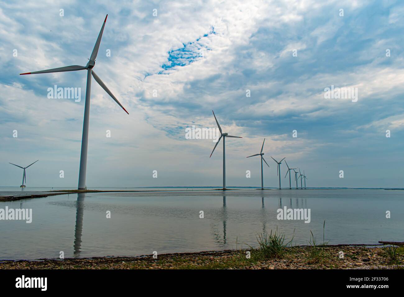 Moderni mulini a vento costruiti su una stretta diga sulla costa occidentale della Danimarca, Nissum Bredning Bay Foto Stock