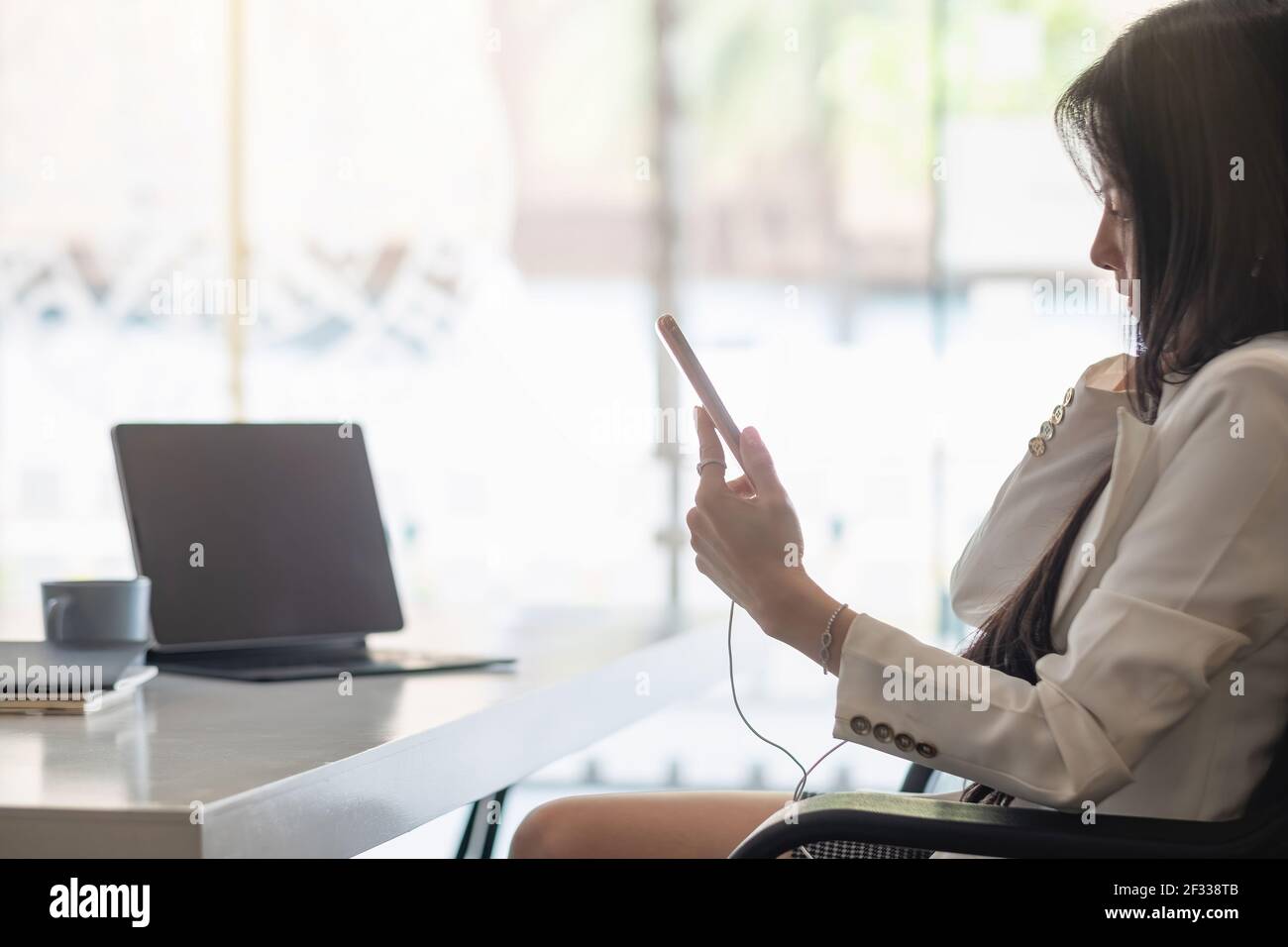 Relax Time - Businesswoman con le cuffie che utilizzano lo smartphone per l'ascolto musica seduto alla scrivania all'interno dell'ufficio Foto Stock