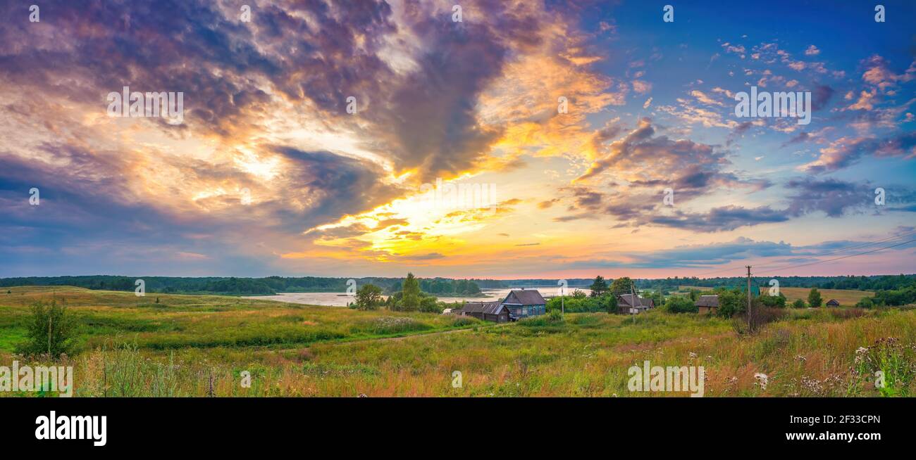 Vista panoramica su un tramonto luminoso sul lago e sul vecchio villaggio in campagna Foto Stock