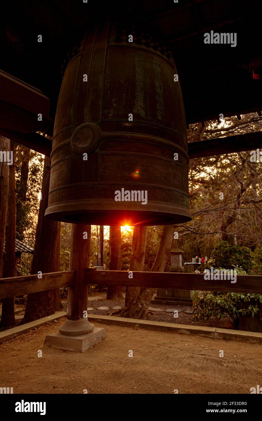 Grande campana di ottone in un tempio giapponese Shinto a Sendai, in Giappone chiamato Rinno-ji Tempio con alberi di pino e il tramonto sullo sfondo Foto Stock