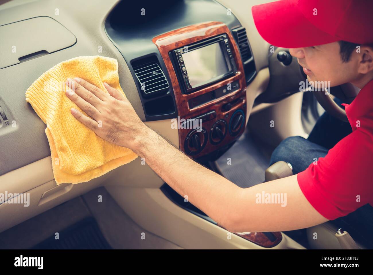 Un uomo che pulisce gli interni dell'automobile - concetto di dettaglio e di valeting dell'automobile, effetto di tono vintage Foto Stock
