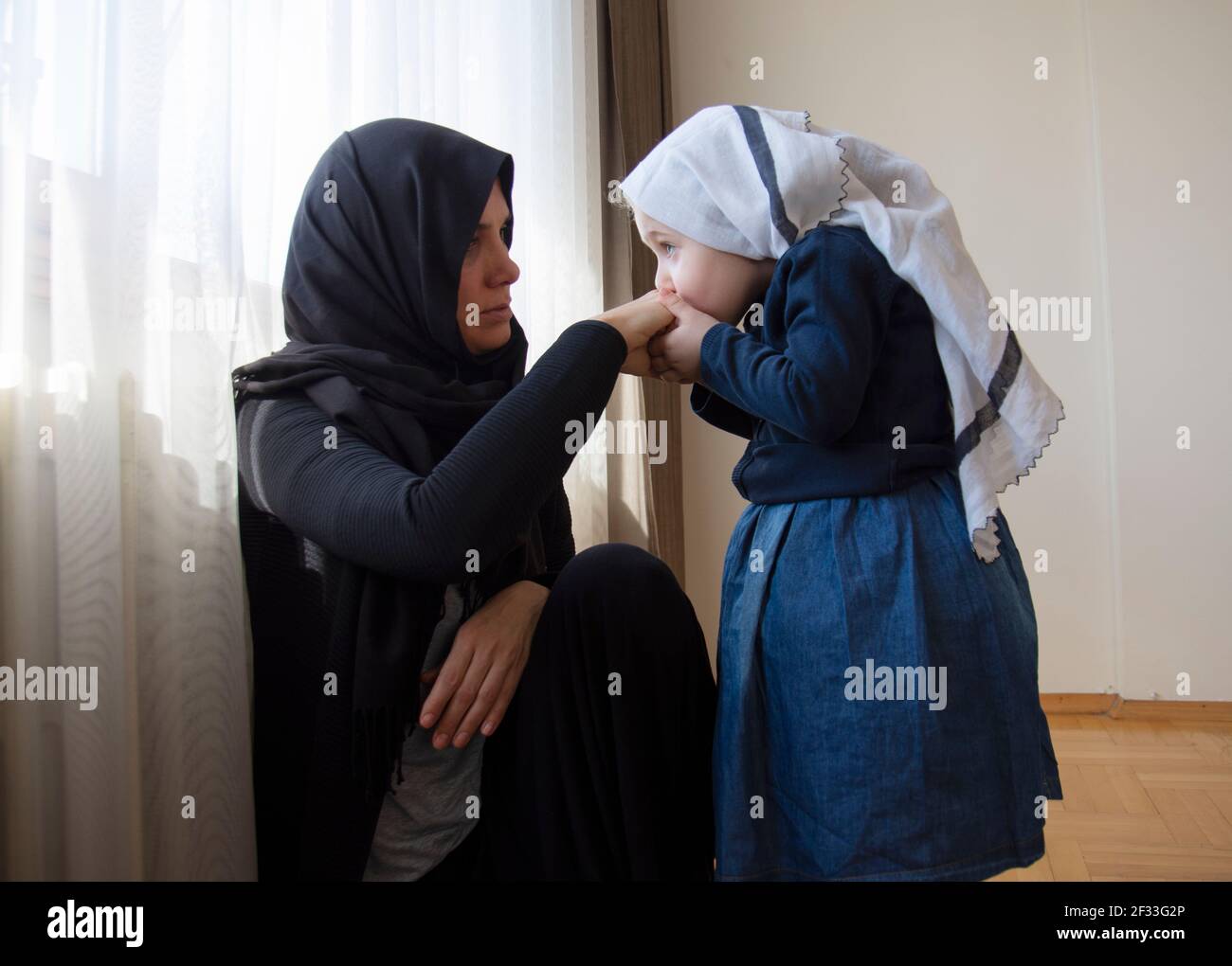 Bambina andher madre che si guarda l'un l'altro. Donna hijab e sua figlia. Aiuto mubarak musulmano Foto Stock