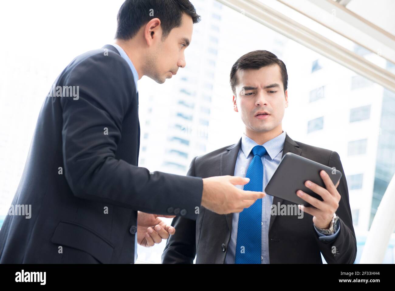 Uomini d'affari che guardano al tablet pc, parlano di lavoro Foto Stock