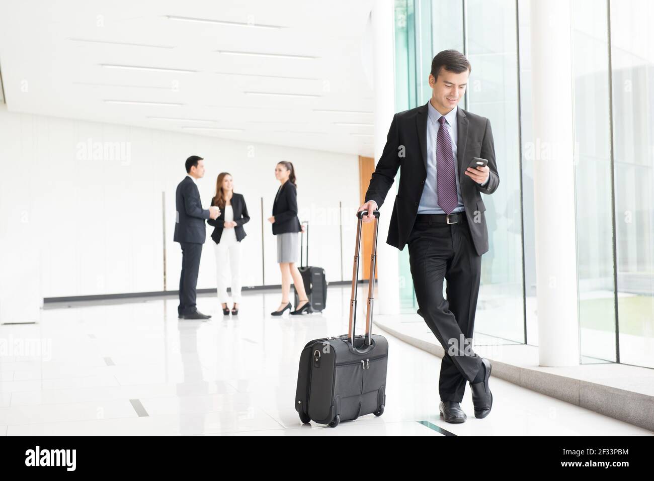 Uomini d'affari (assistenti di volo) con bagagli nel corridoio dell'edificio (terminal aeroportuale) Foto Stock