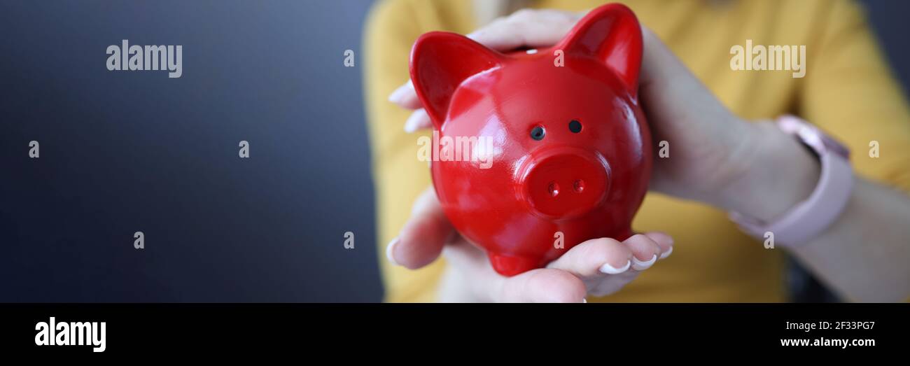 Donna che tiene la banca del piggy rosso nel suo closeup delle mani Foto Stock