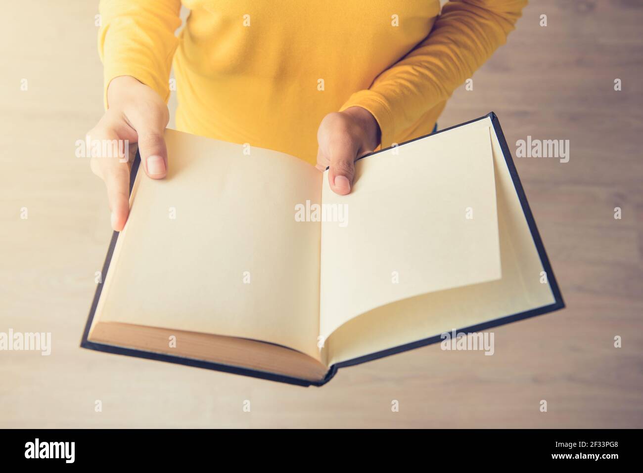 Libro di apertura delle mani della giovane donna in piedi - vista dall'alto, effetto tono vintage Foto Stock