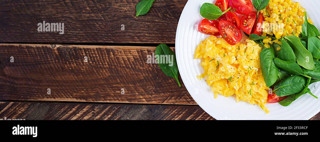 Colazione. Uova strapazzate con pomodori ciliegini, spinaci e mais. Vista dall'alto, banner, sopra Foto Stock