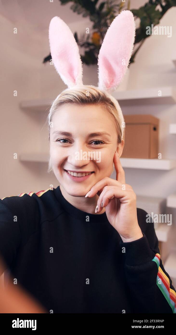 Felice giovane donna che ha una videochiamata mentre indossa le orecchie conigliate. Foto di alta qualità Foto Stock