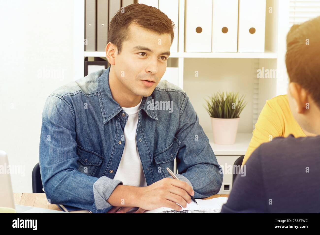 Bell'uomo d'affari che indossa una camicia jean casual che discute i documenti nel riunione Foto Stock
