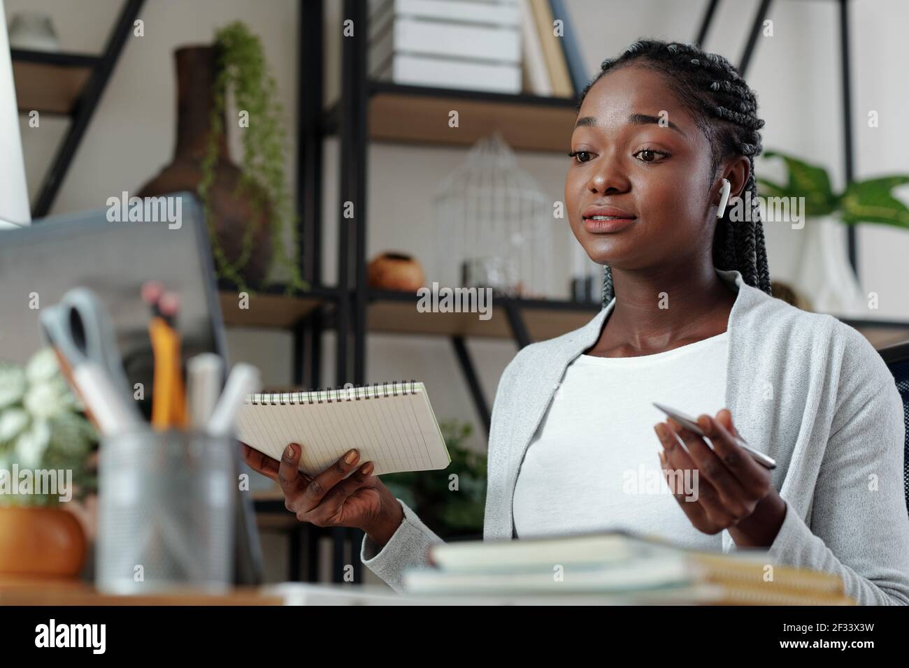 Bella giovane donna nera con notebook in mano avendo online incontro con il cliente o il collaboratore e discussione del progetto Foto Stock