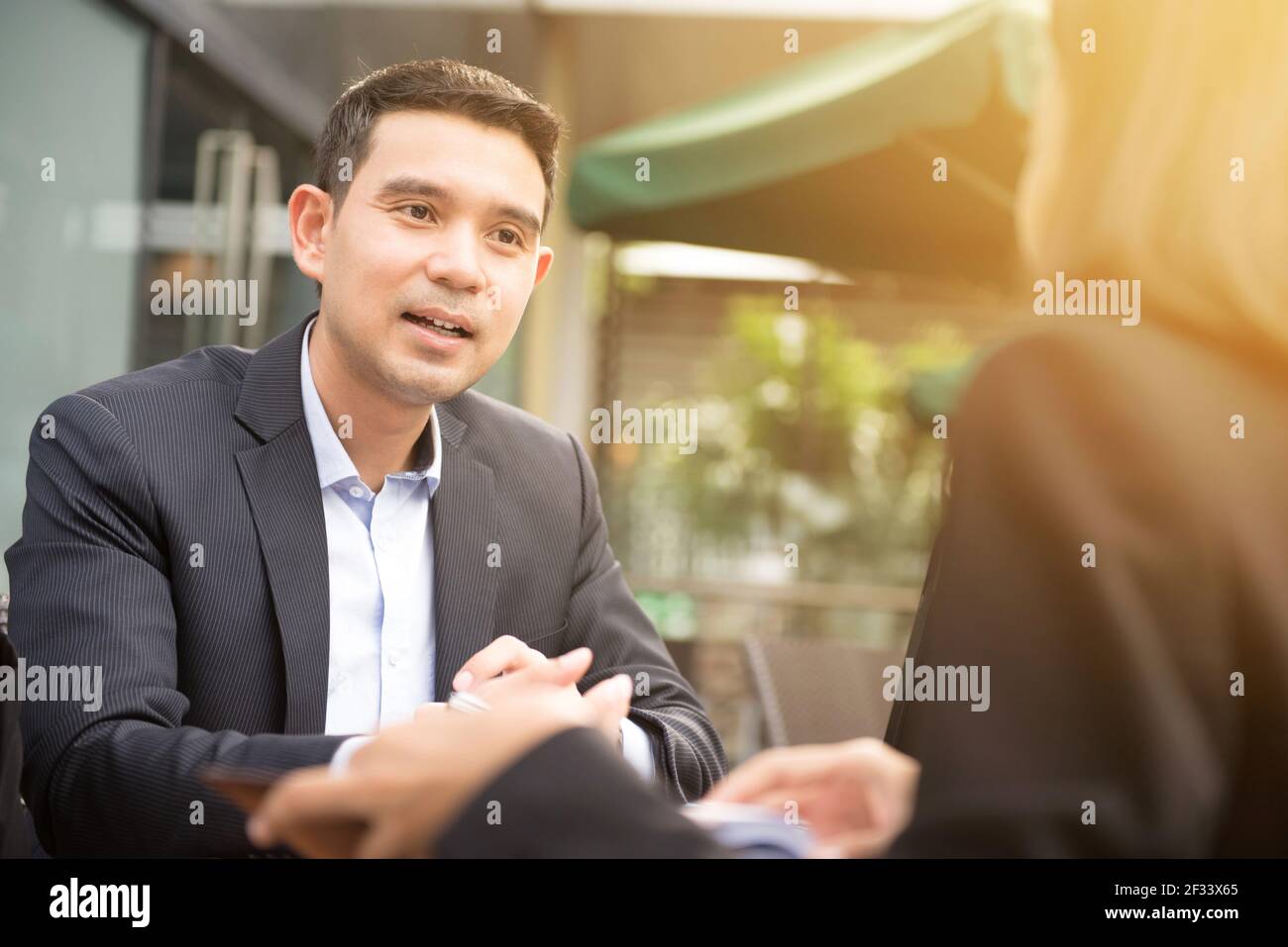 Uomo d'affari asiatico che parla con una donna d'affari in un caffè all'aperto Foto Stock