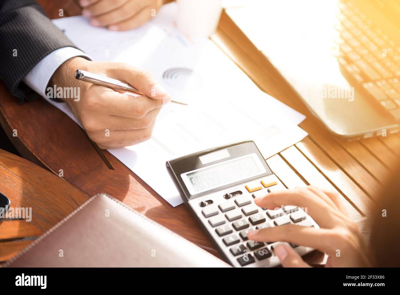 Consulente finanziario che lavora con il cliente, calcolando e analizzando i dati al tavolo del bar Foto Stock