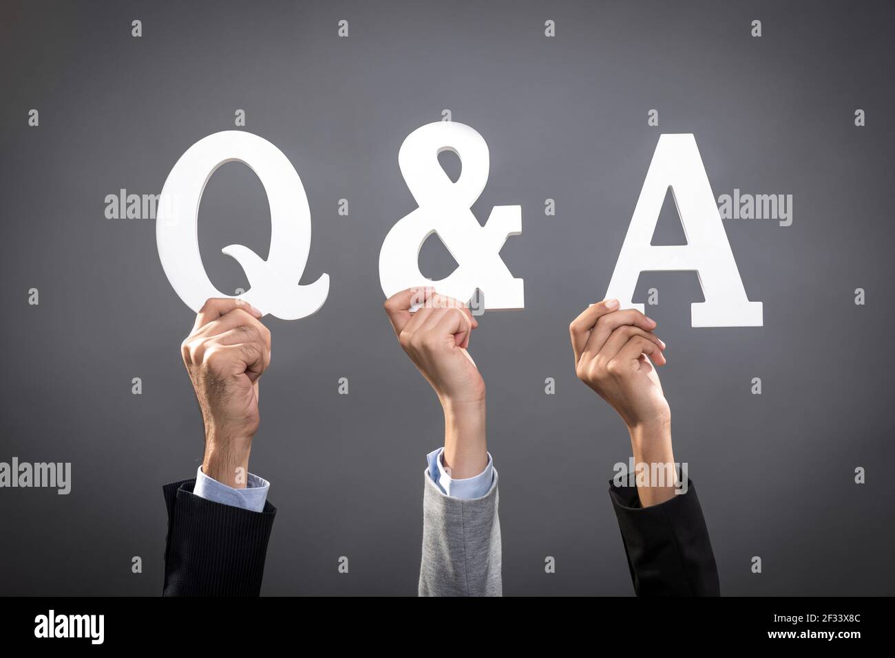 Uomini d'affari che alzano le mani con lettere che mostrano Q & A. segno Foto Stock