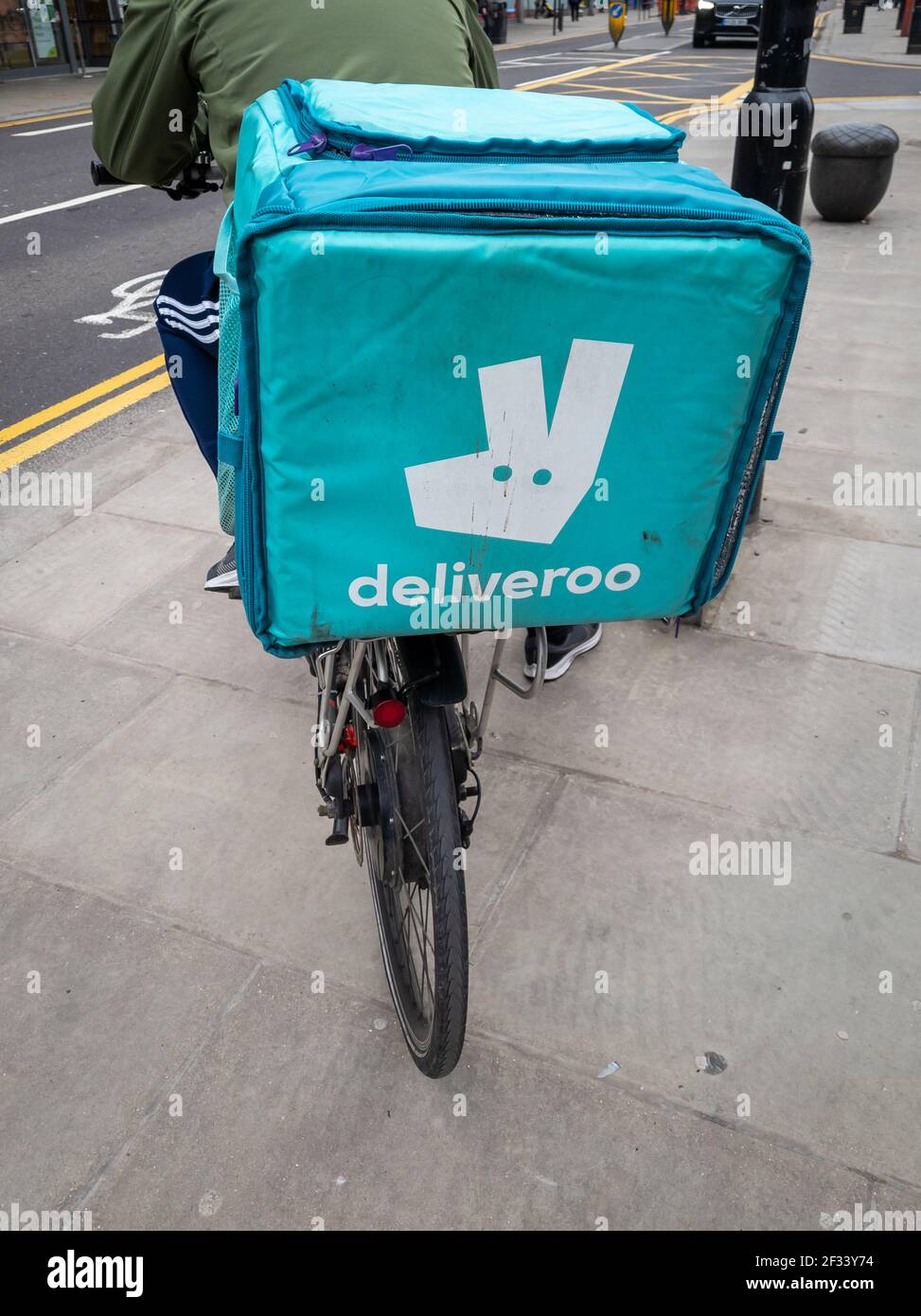 Un ciclista che lavora per l'azienda di consegna di cibo domestico in linea Deliveroo. Foto Stock