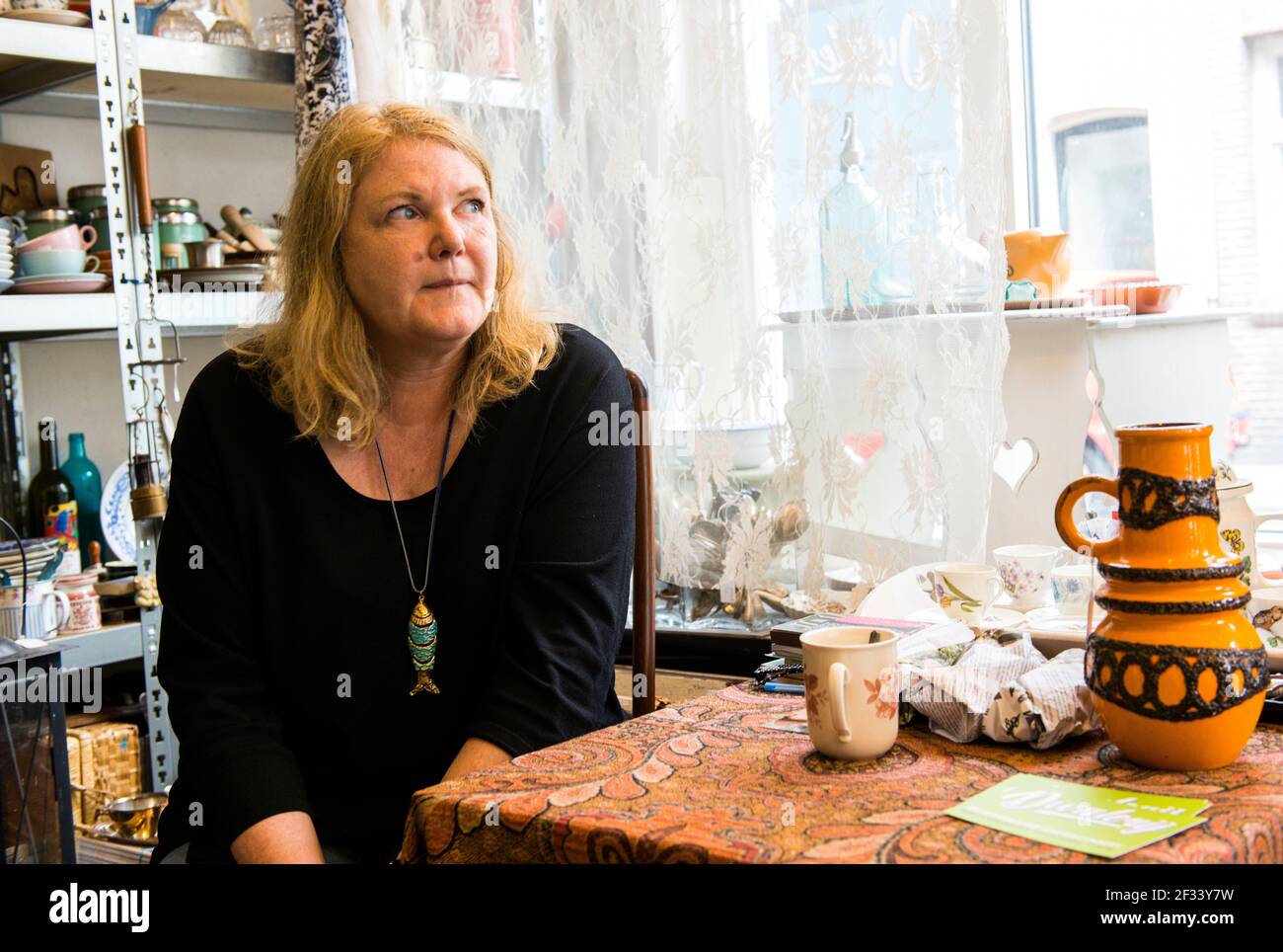 Tilburg, Paesi Bassi. Adulto, donna caucasica mantenendo il proprio negozio di vintage articoli per la casa e complementi di arredo. Foto Stock