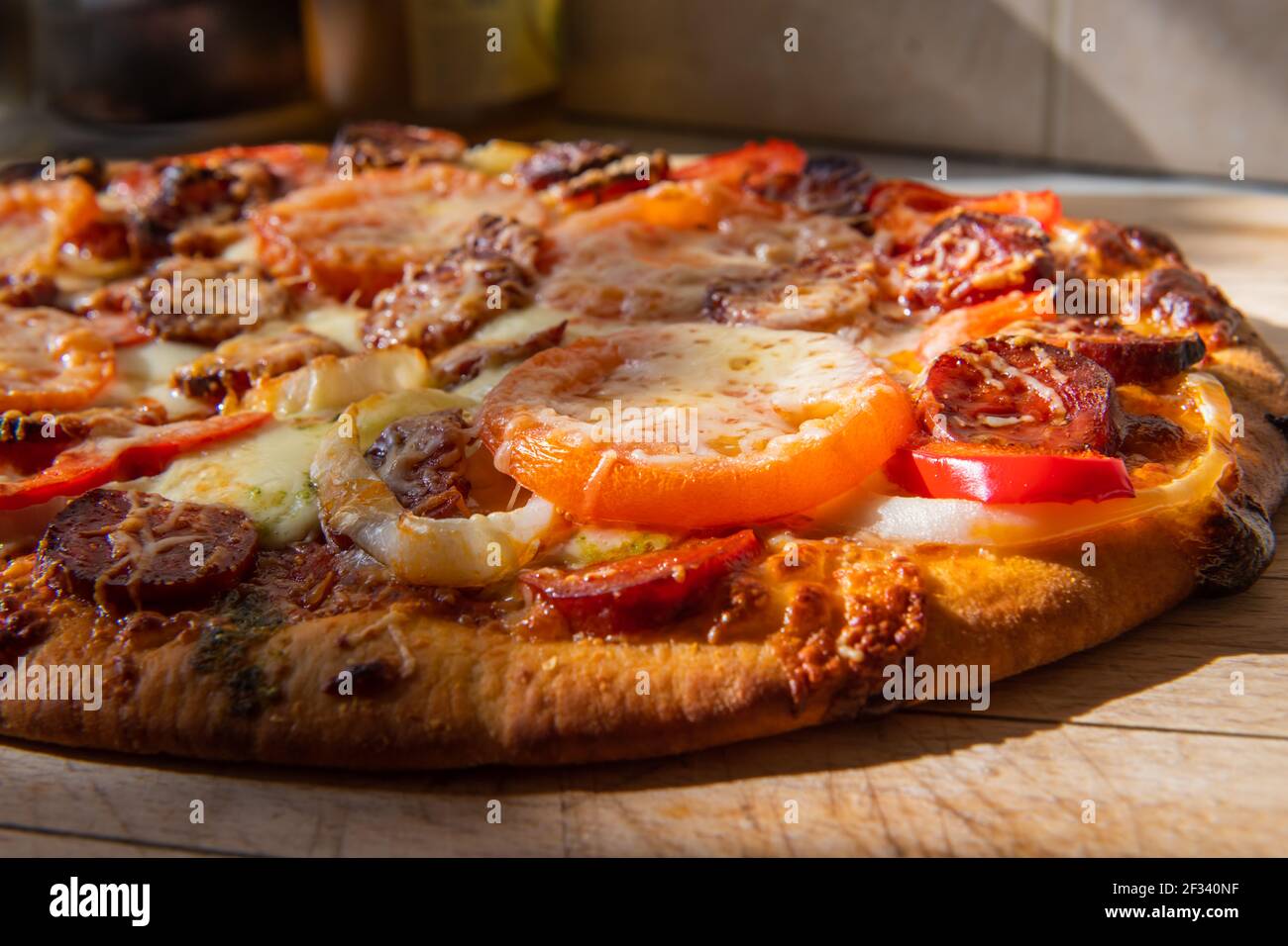 Una pizza fatta in casa con condimenti a base di carne e verdure. Foto Stock