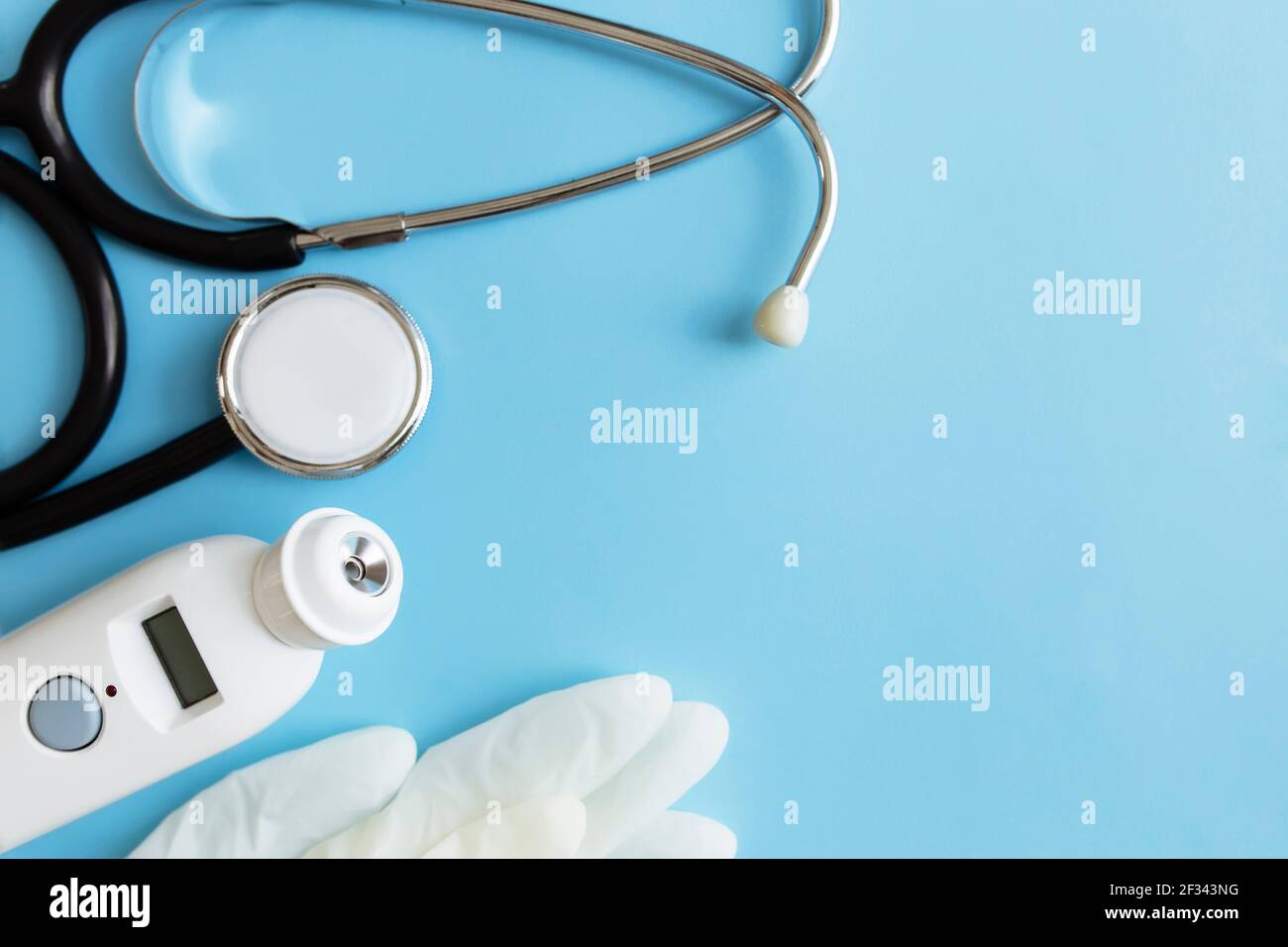Concetto di trattamento medico. Termometro elettronico, fonendoscopio o stetoscopio, guanti bianchi su sfondo blu. Foto di alta qualità Foto Stock