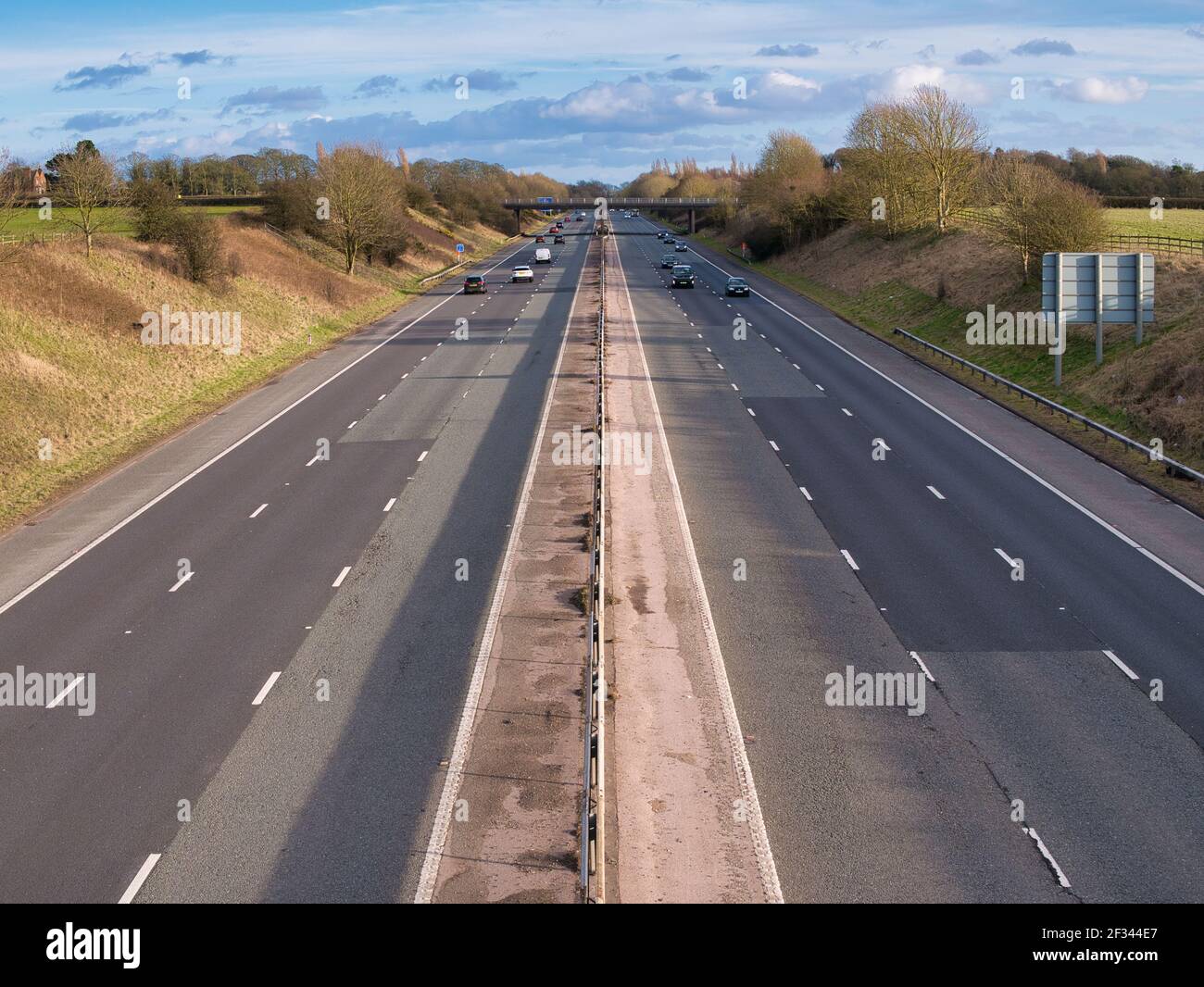 Traffico leggero su un tratto rettilineo di autostrada nel Regno Unito in una giornata di sole in inverno. Le riparazioni al fondo stradale sono visibili in primo piano. Foto Stock