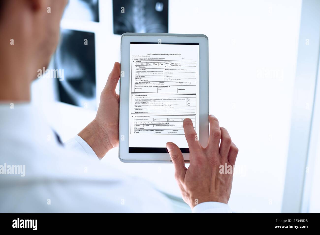 il medico sta utilizzando un tablet digitale per compilare il modulo di registrazione. Foto Stock