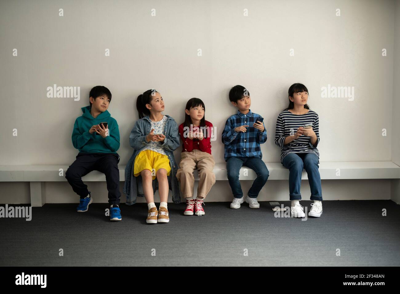 Bambini che guardano lontano e hanno uno smartphone Foto Stock