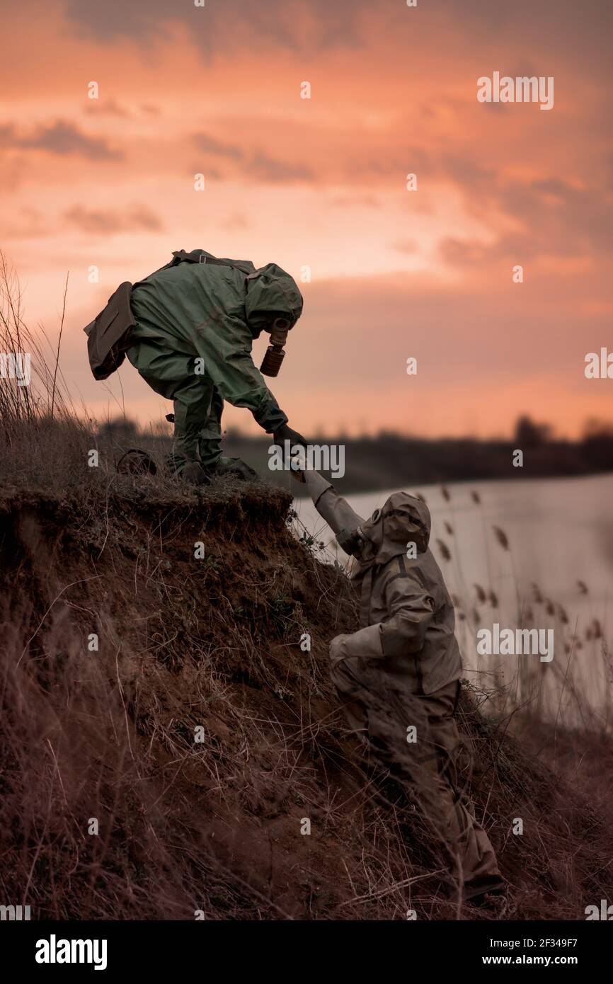 Le persone in maschere a gas e tute di protezione dalle radiazioni corrono lontano dalla contaminazione da radiazioni. Foto Stock