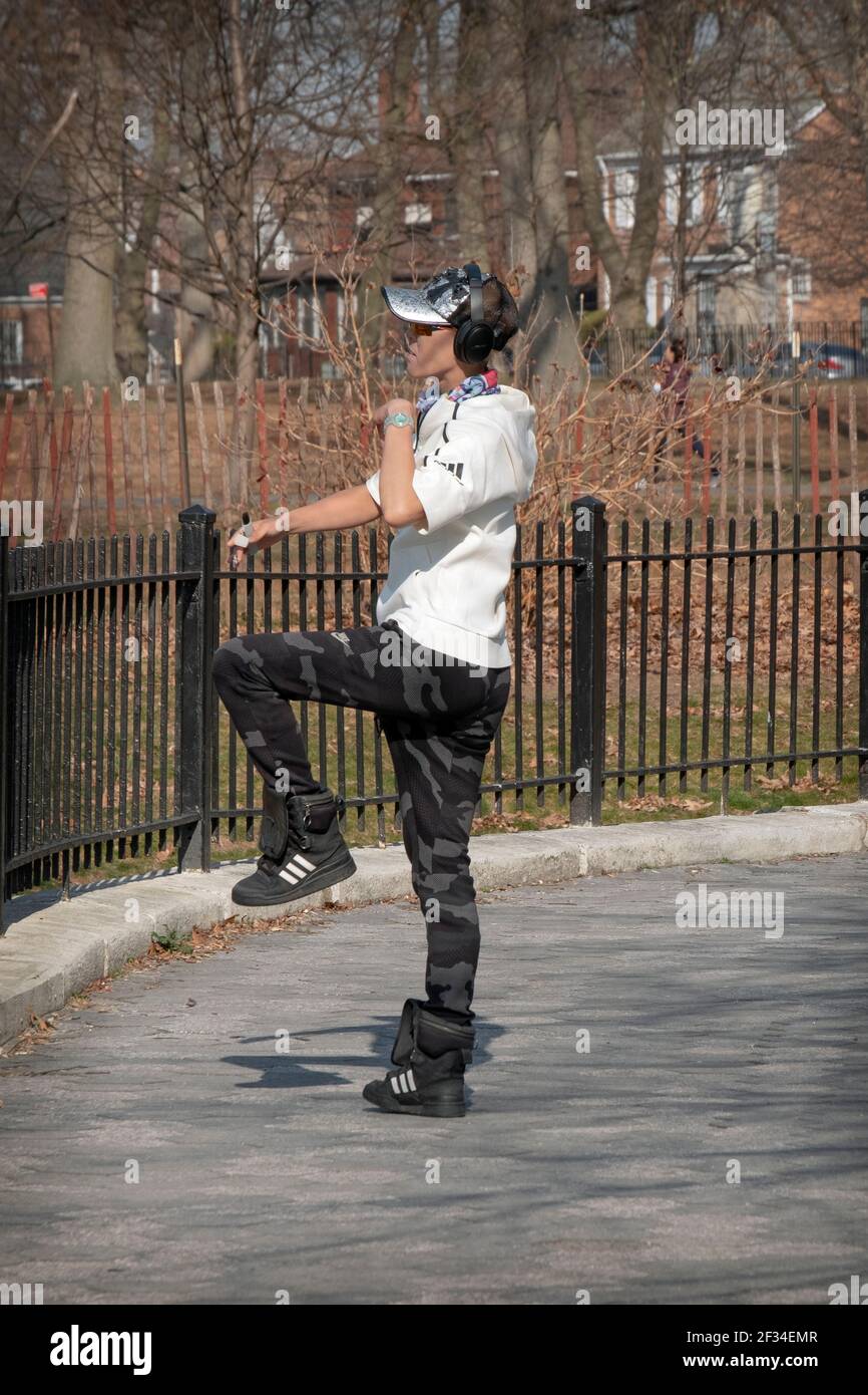 Una donna cinese americana snella misura danze con zavorre delle gambe come forma di esercizio. In un parco a Queens, New York City. Foto Stock