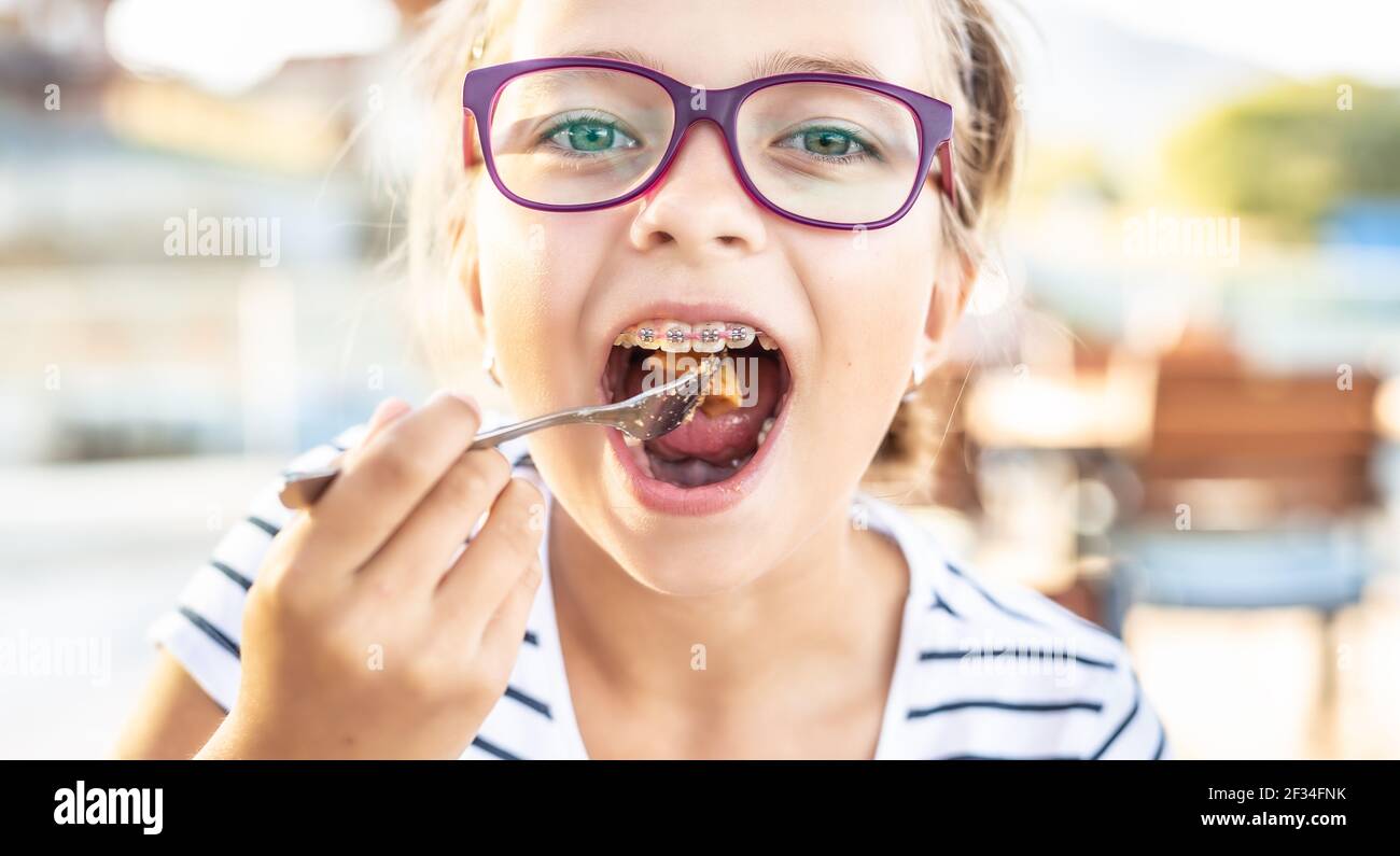 Giovane ragazza che indossa occhiali e bretelle mette il cibo sulla  forchetta in bocca Foto stock - Alamy