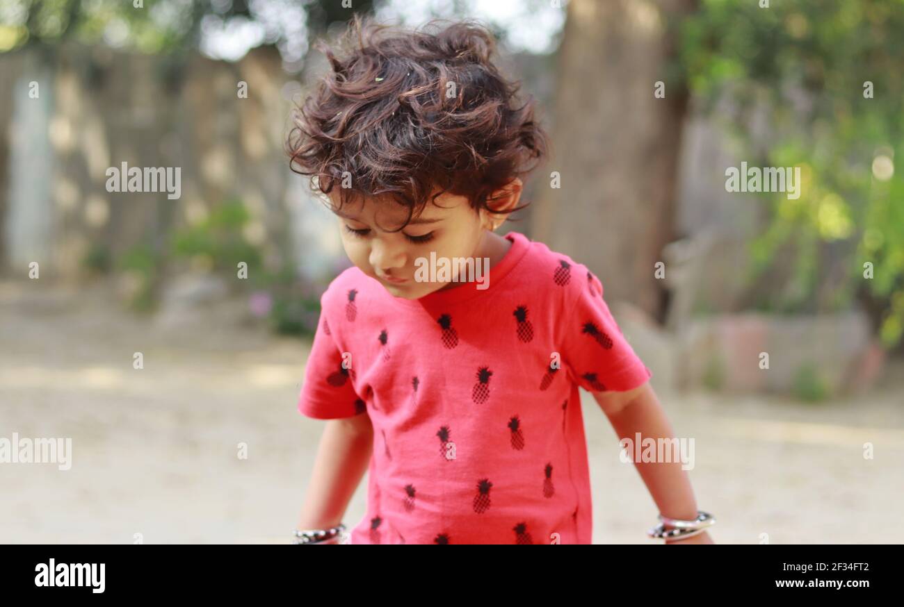 Un piccolo ragazzo di origine indiana che guarda la terra, india.Concept per le gioie dell'infanzia, i ricordi dell'infanzia, le espressioni del viso del bambino e il linguaggio del corpo , p. Foto Stock