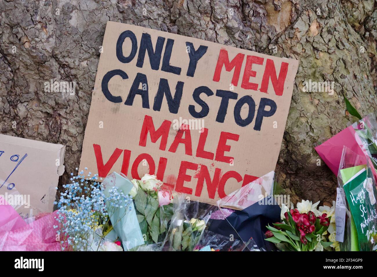 Un segno che legge 'solo gli uomini possono fermare la violenza maschile' e. Fiori messi in Clapham Common in omaggio a Sarah Everard Foto Stock