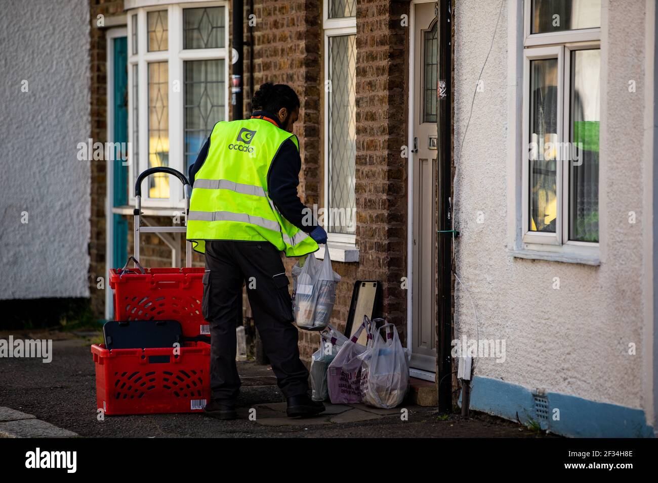 Un autista di consegna di Ocado che cali fuori da una casa di clienti durante la pandemia di Covid 19. Foto Stock