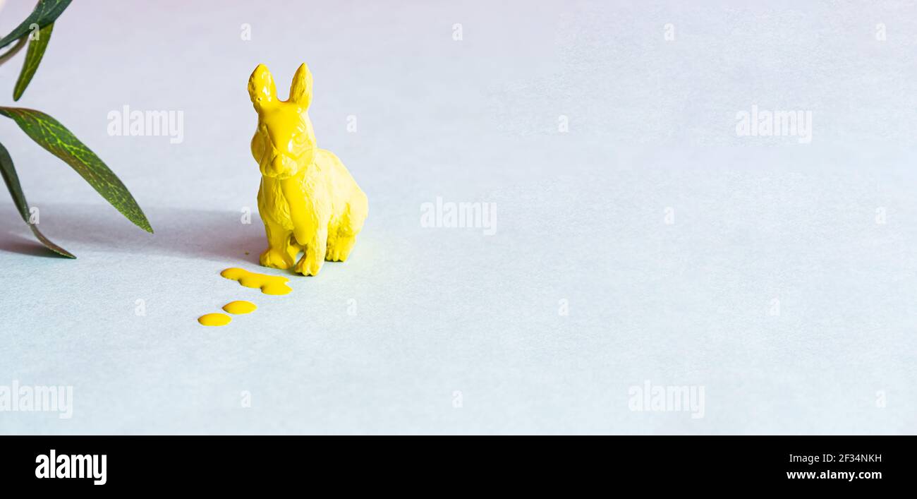 Coniglietto di Pasqua giallo in vernice su sfondo blu. Concetto di pasqua moderno, spazio di copia. Layout di cartoline creative minimo. Foto Stock