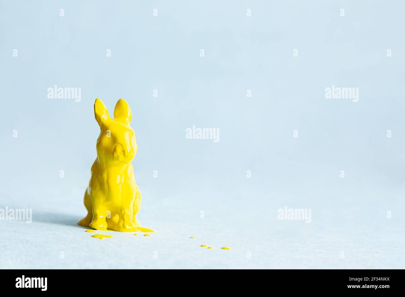 Coniglietto di Pasqua giallo in vernice su sfondo blu. Concetto di pasqua moderno, spazio di copia. Layout di cartoline creative minimo. Foto Stock