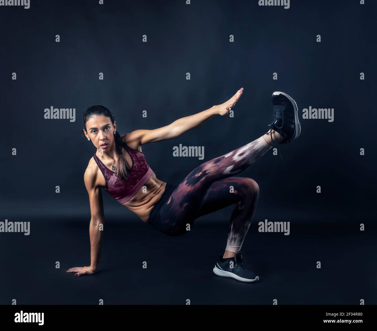 donna che esegue esercizi di fitness isolato su sfondo scuro. Foto Stock