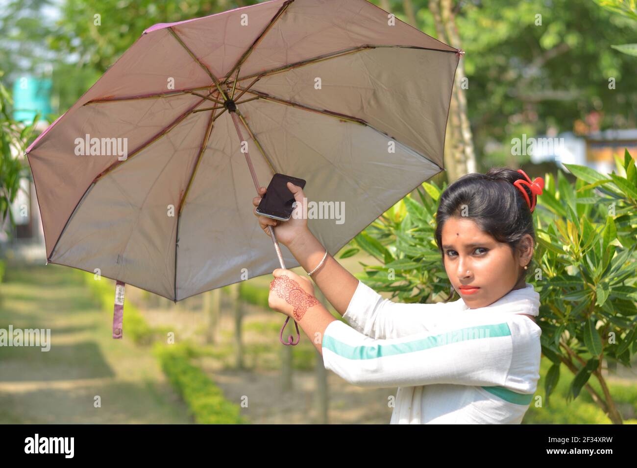Indiano Bengalese adolescente ragazza cotone bianco indossando salwar kameez e dhupatta aprendo un ombrello, messa a fuoco selettiva Foto Stock