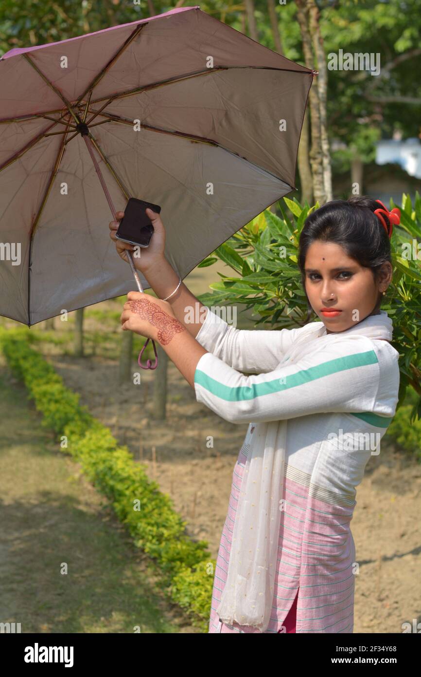 Indiano Bengalese adolescente ragazza cotone bianco indossando salwar kameez e dhupatta aprendo un ombrello, messa a fuoco selettiva Foto Stock