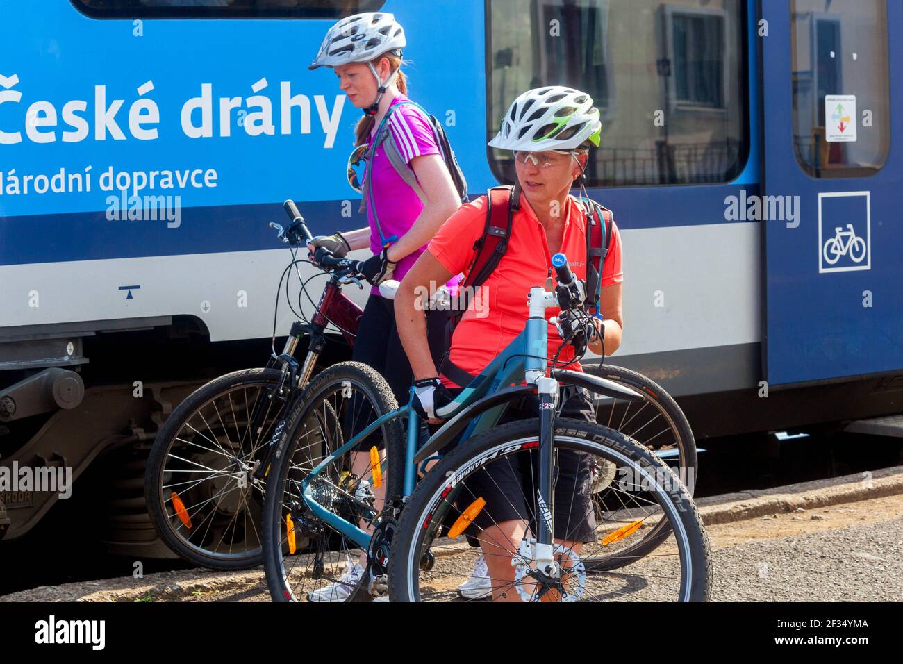 Due giovani donne che viaggiano in bicicletta su una piattaforma ferroviaria Repubblica Ceca Ceske Drahy ferrovie Foto Stock