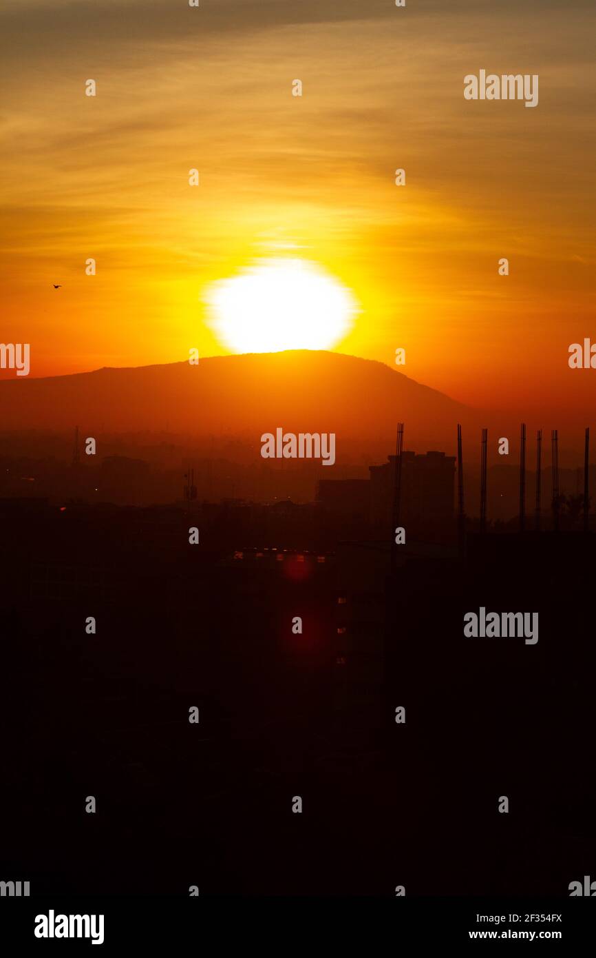 NAIROBI, KENYA - 17 aprile 2020: Sole che sorge su una collina mentre la città è in silhoutte Foto Stock