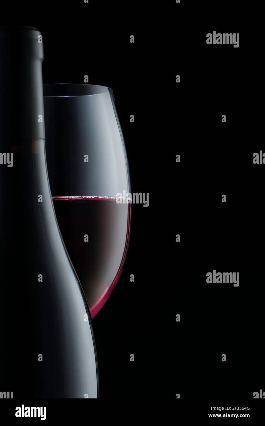 Elegante bottiglia e bicchiere di vino rosso, elementi da primo piano, spazio per la copia. Foto verticale. Foto Stock