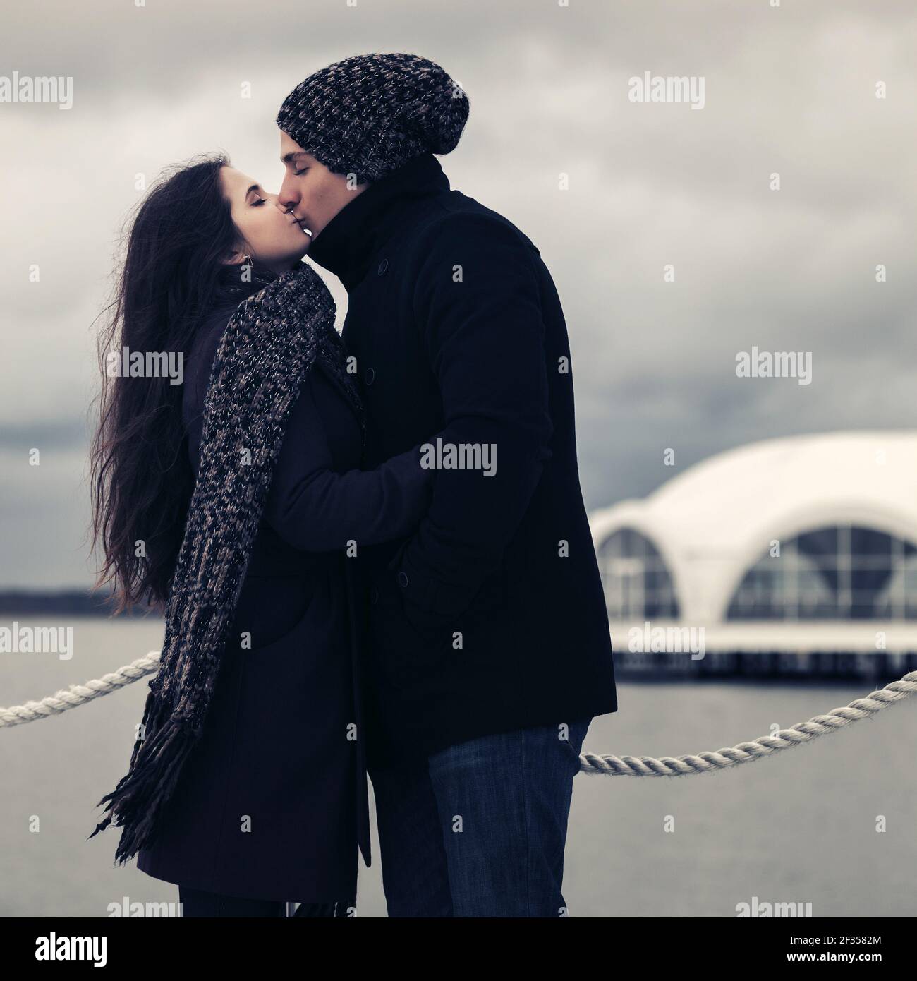 Felice giovane coppia di moda in amore baciare outdoor elegante uomo e donna in classico cappotti bania e sciarpa Foto Stock